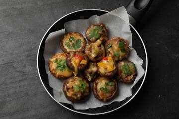 Tasty stuffed mushrooms in frying pan on black table, top view