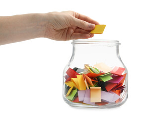 Woman taking color paper piece form glass jar on white background, closeup