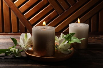 Burning candles and lily flowers on wooden table, closeup