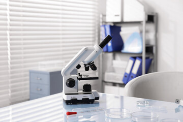 Petri dishes and microscope on white table in laboratory