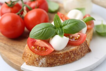 Tasty sandwich with mozzarella cheese, tomatoes and basil on light table, closeup