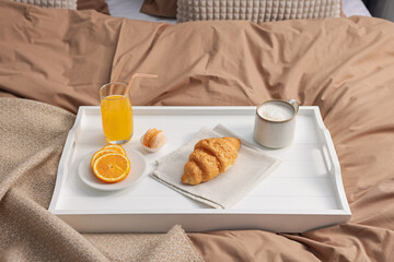 Tray with delicious breakfast on bed indoors, closeup
