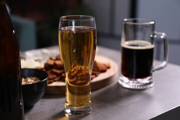 Beer and snacks on grey table indoors, closeup