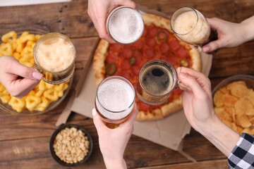 Friends with beer and snacks at wooden table, top view