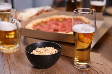 Beer and snacks on wooden table indoors, closeup
