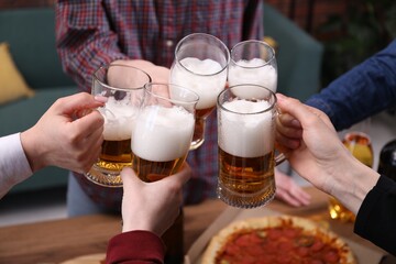 Friends clinking glasses of beer at table, closeup
