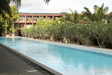 Outdoor swimming pool, building and green plants at luxury resort