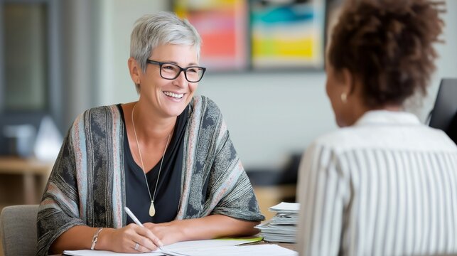 Bright-eyed HR specialist engages in a confidential mental health consultation, listening attentively to a client's concerns in a modern office filled with natural light