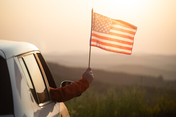 Man in the car holding a waving american USA flag.