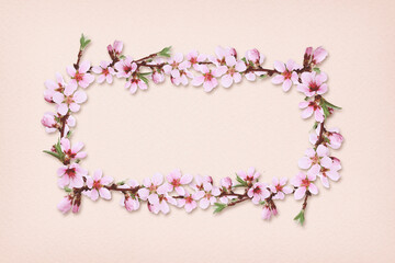 Spring peach twigs in a floral frame on pink paper background.