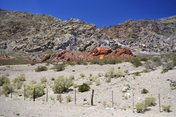 The stony foot of the mountain is strewn with large stones under the scorching sun. Desert hot arid landscape.