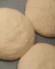 Fresh raw dough balls rising on a smooth surface before baking, perfect for pizza, bread, or langos preparation, high-resolution food stock photo