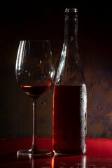 bottle and glass of rosé wine with abstract background and side lighting