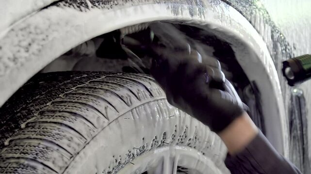 Detailing car cleaning with foam and soft brush. Process of detailing sports car headlights wash with soap foam and brush at the service
