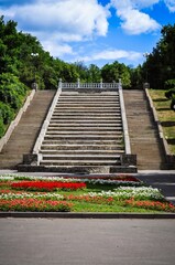 Stone staircase with colorful flowers, trees, and a bright blue sky