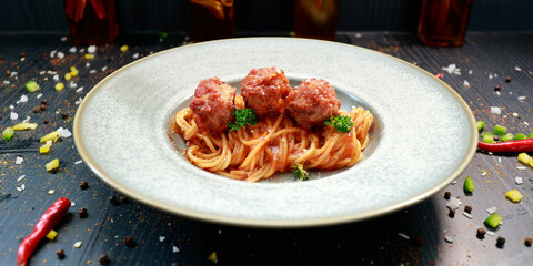 close up of a plate with pasta and meatballs inside