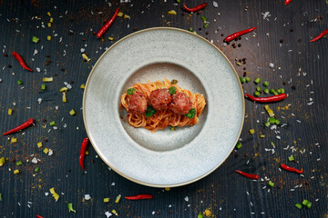 close up of a plate with pasta and meatballs inside