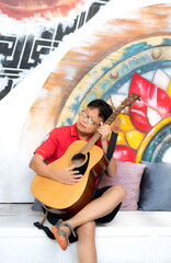 Korean , Japanese man holding an acoustic guitar  in room