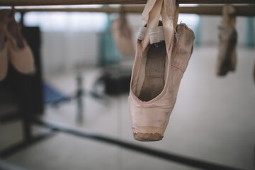 Old pointe shoes hang on ballet barre