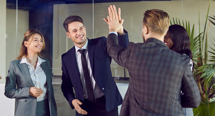 Happy businessmen high five in lobby of modern office, close-up. Successful multicultural team of...