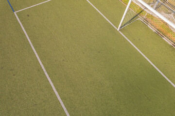 athletic field texture green synthetic grass and a white goal frame aerial drone view