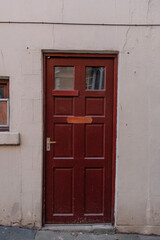 Rustic red door standing alone against a weathered wall in an urban alley at midday