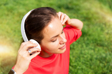 Fototapeta premium Relaxed young female in red t-shirt listening to music outdoors