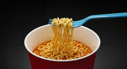 Instant noodles in red cup with blue fork on dark background  