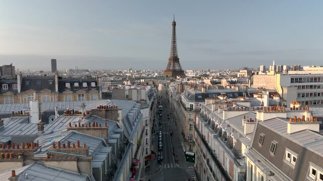 Aerial drone view of the sleepy streets of Paris, France, overlooking the famous Eiffel Tower and Champ de Mars at sunrise or sunset. Low motion over the rooftops. Cinematic 4k. Europe from above.