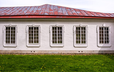 The wall of an old stone building with an iron roof and windows.