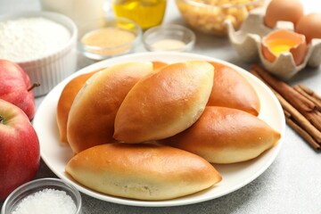 Tasty baked patties and ingredients on light grey table, closeup