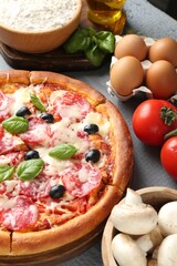 Tasty pizza and ingredients on grey wooden table, closeup