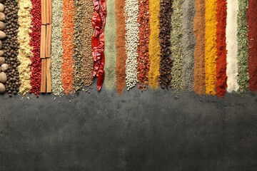 Many different spices on black table, flat lay. Space for text