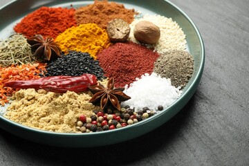 Different aromatic spices on dark textured table, closeup