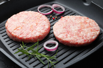Fresh raw patties for burger and spices in frying pan on table, closeup