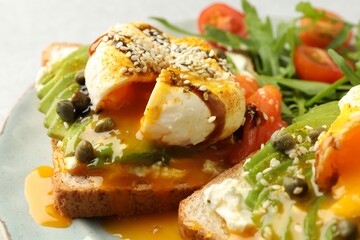 Delicious sandwiches with avocado, poached egg and salmon on table, closeup