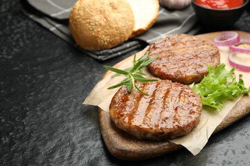 Delicious hamburger patties and spices on black table, closeup. Space for text