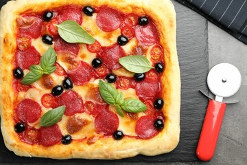 Tasty homemade pizza and cutter on grey table, top view