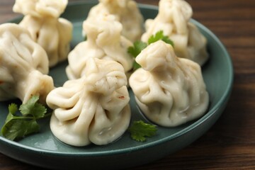 Delicious khinkali with cilantro on wooden table, closeup
