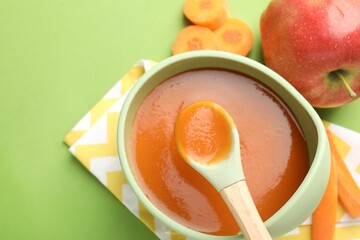 Baby food. Tasty puree in bowl and ingredients on green background, above view. Space for text