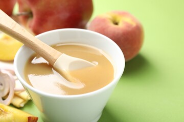 Baby food. Tasty puree in bowl and ingredients on green background, closeup. Space for text