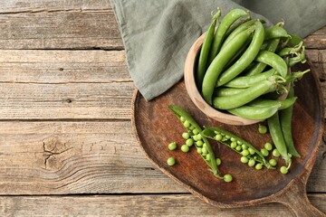 Fresh ripe green peas on wooden table, flat lay. Space for text