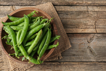 Fresh ripe green peas on wooden table, top view. Space for text