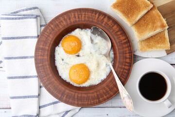 Half-boiled eggs in plate, coffee and toasted bread on white wooden table, flat lay