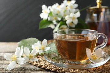Aromatic jasmine tea and flowers on wooden table, closeup