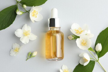 Cosmetic product and jasmine flowers on light background, flat lay