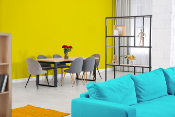 Dining table and chairs near yellow wall in room. Interior design