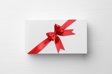 Gift card with red bow on white background, top view