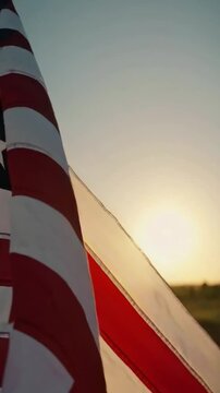 American flag waving at sunset, patriotic United States flag in golden hour light, national symbol of USA with sun flare background