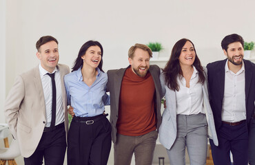 Joyful business people team standing together and embracing each other. Happy company employees men and women hugging, celebrating successful work during team building event and creating friendly team